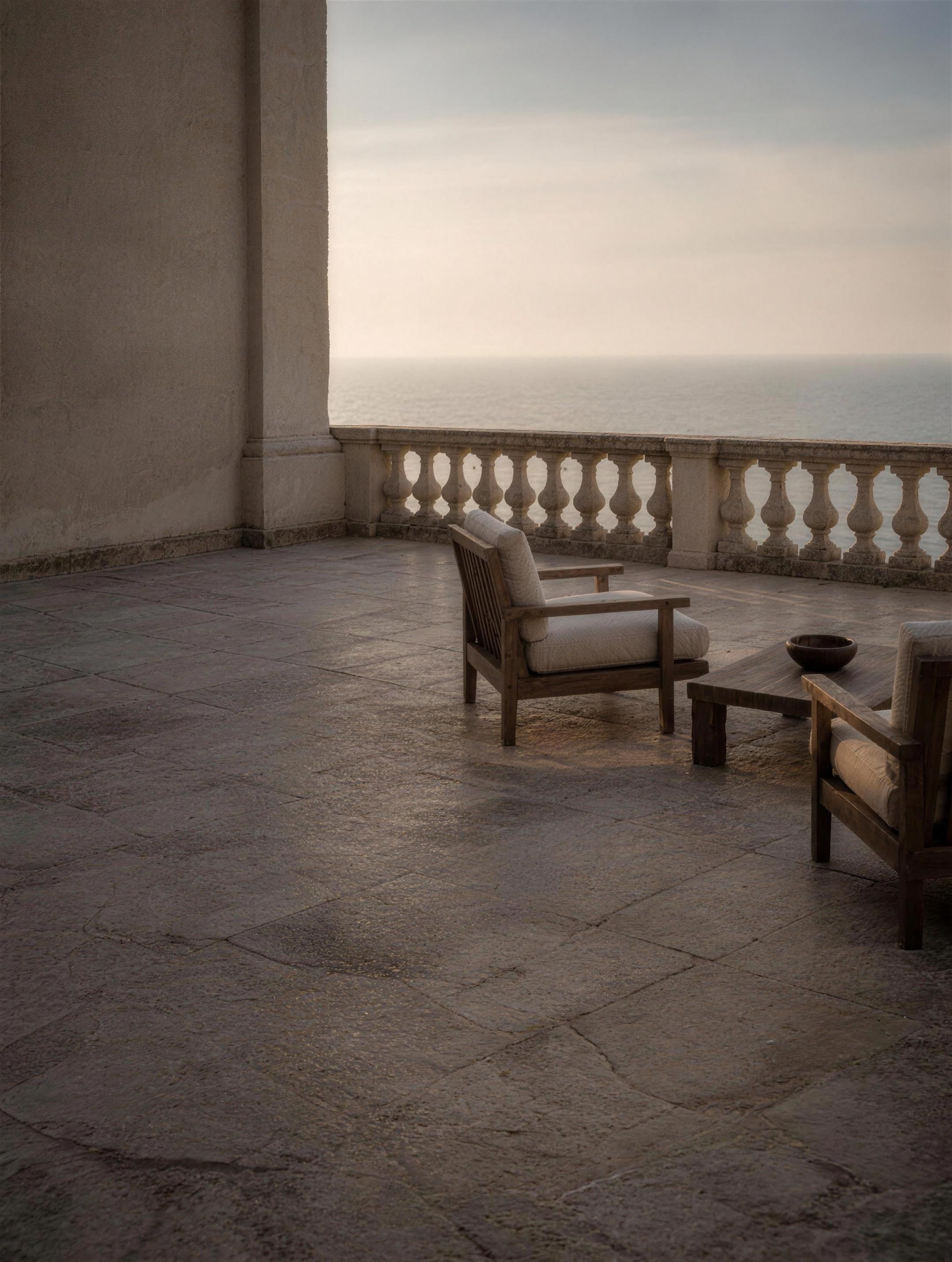 Image d’ambiance — une terrasse de pierre déserte aux premières lueurs, balustrade et brume marine au-delà.